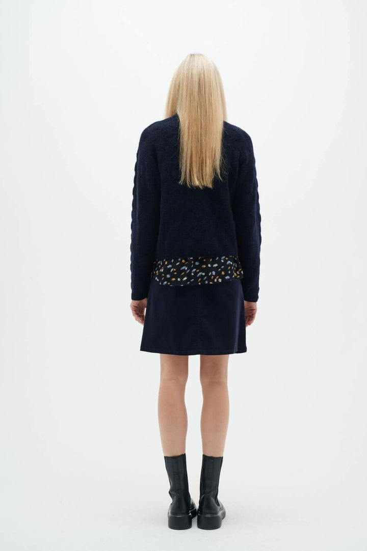 Modèle vue de dos portant la jupe Rylie marine avec un haut en tricot, style élégant et polyvalent.