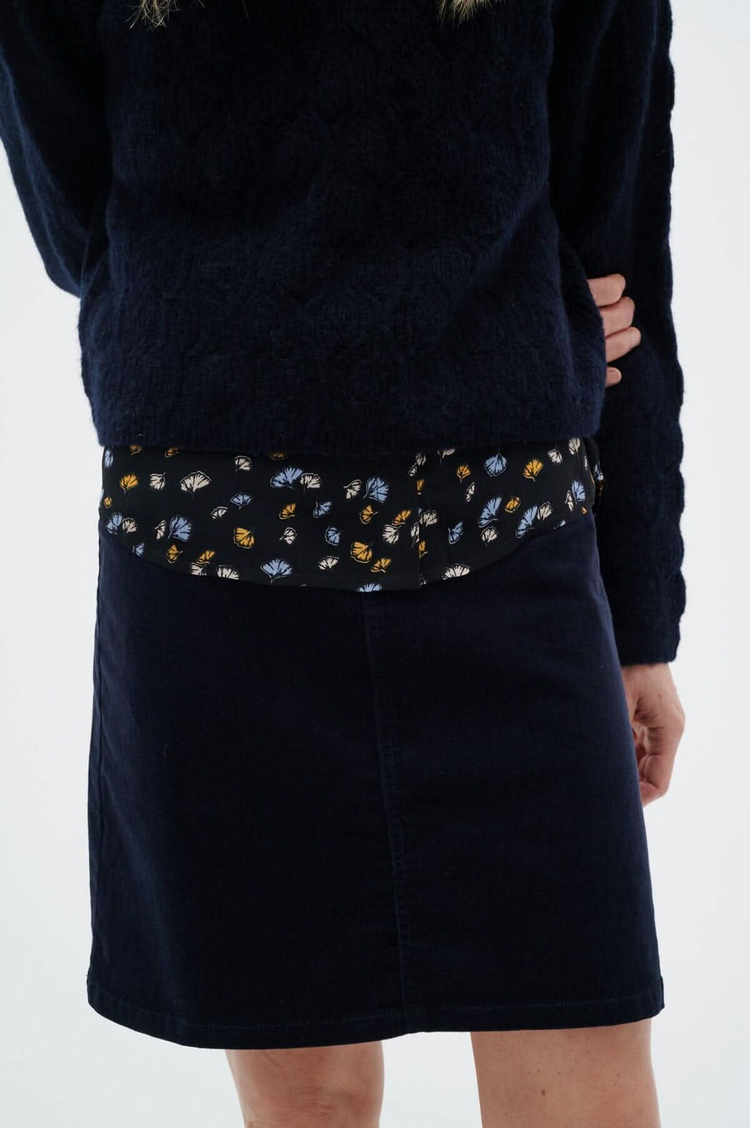 Jupe Rylie d'Inwear, marine, coupe en A, portée avec un pull noir, pour une allure élégante et polyvalente.