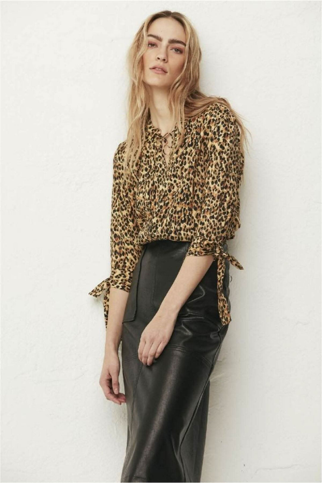 Modèle portant une blouse imprimée léopard et une jupe effet cuir, look tendance et élégant.