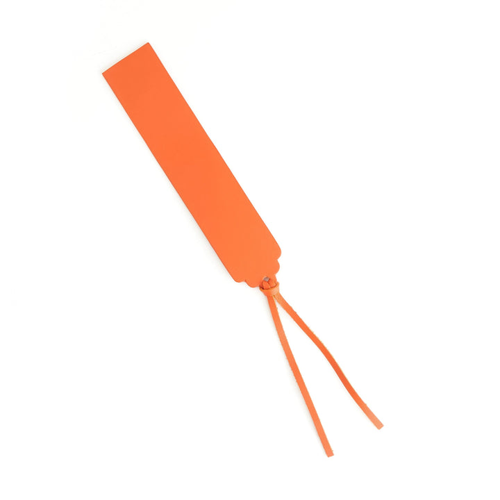 Handmade orange leather bookmark with decorative ribbon for stylish page marking.