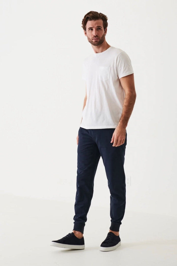 Homme portant un t-shirt léger en coton pima et un pantalon bleu, posé sur fond blanc.