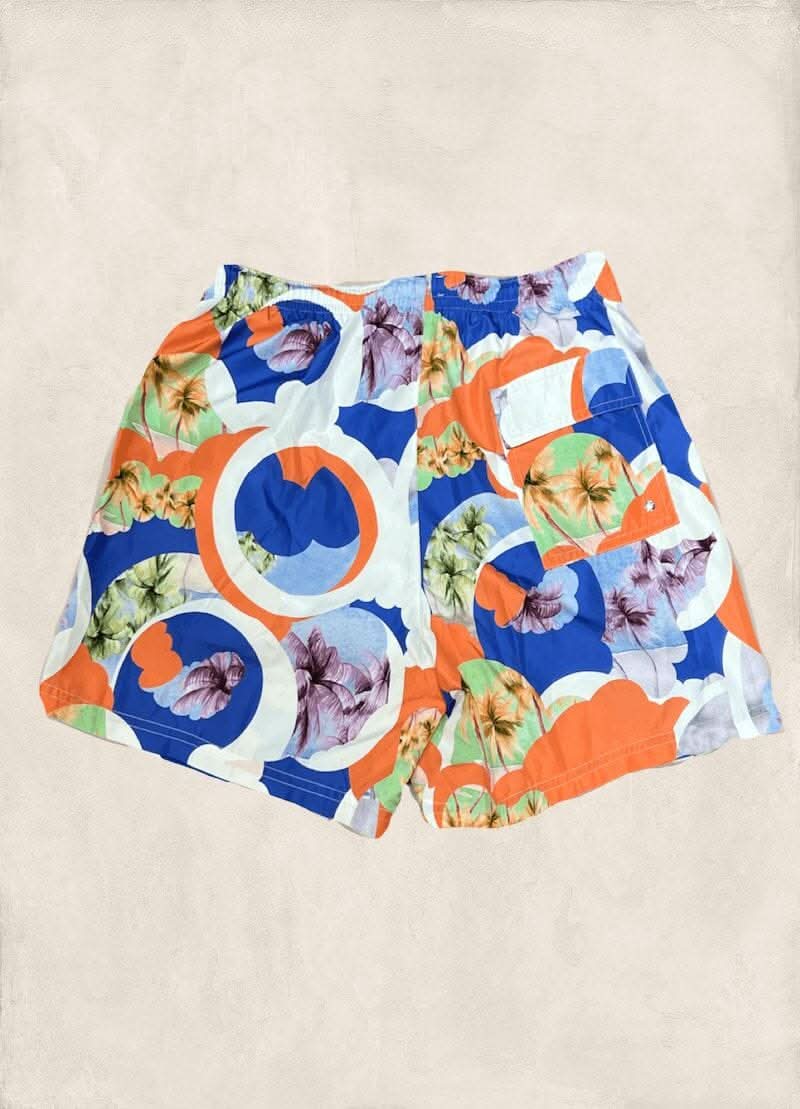 Maillot de bain coloré avec motifs floraux et géométriques en bleu, orange et blanc, parfait pour l'été.