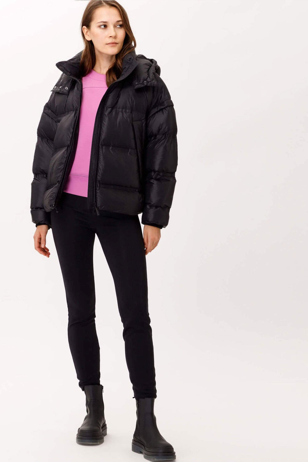 Manteau Filippa noir à manches enlevables et capuchon amovible, porté avec un t-shirt rose et un pantalon noir.