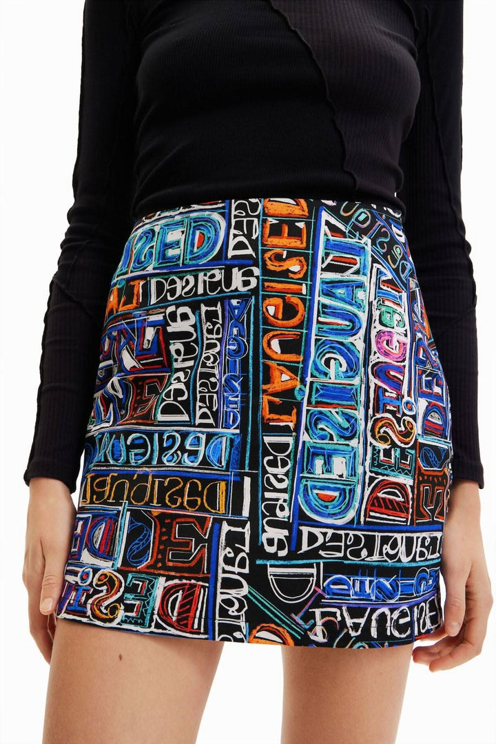 Mini-jupe slim taille haute avec un imprimé logo arty coloré par Javier Mariscal, portée avec un haut noir.
