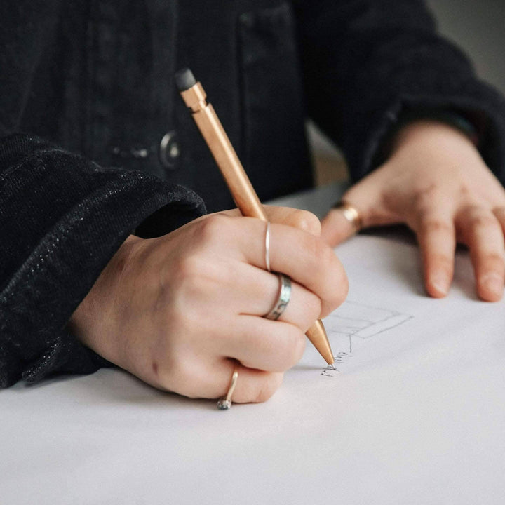 Main image of a person sketching with a modern gold pencil, showcasing creativity and artistry.