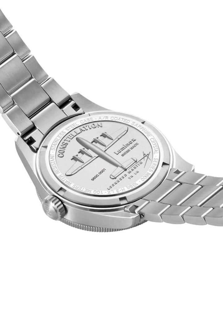 Montre Constellation 9601.M avec fond argenté, bracelet en acier et gravures détaillées à l'arrière.