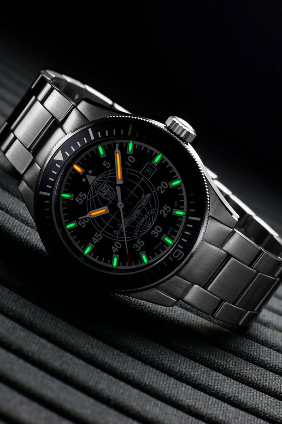 Montre automatique avec cadran noir, bracelet en acier inoxydable, et aiguilles luminescentes.