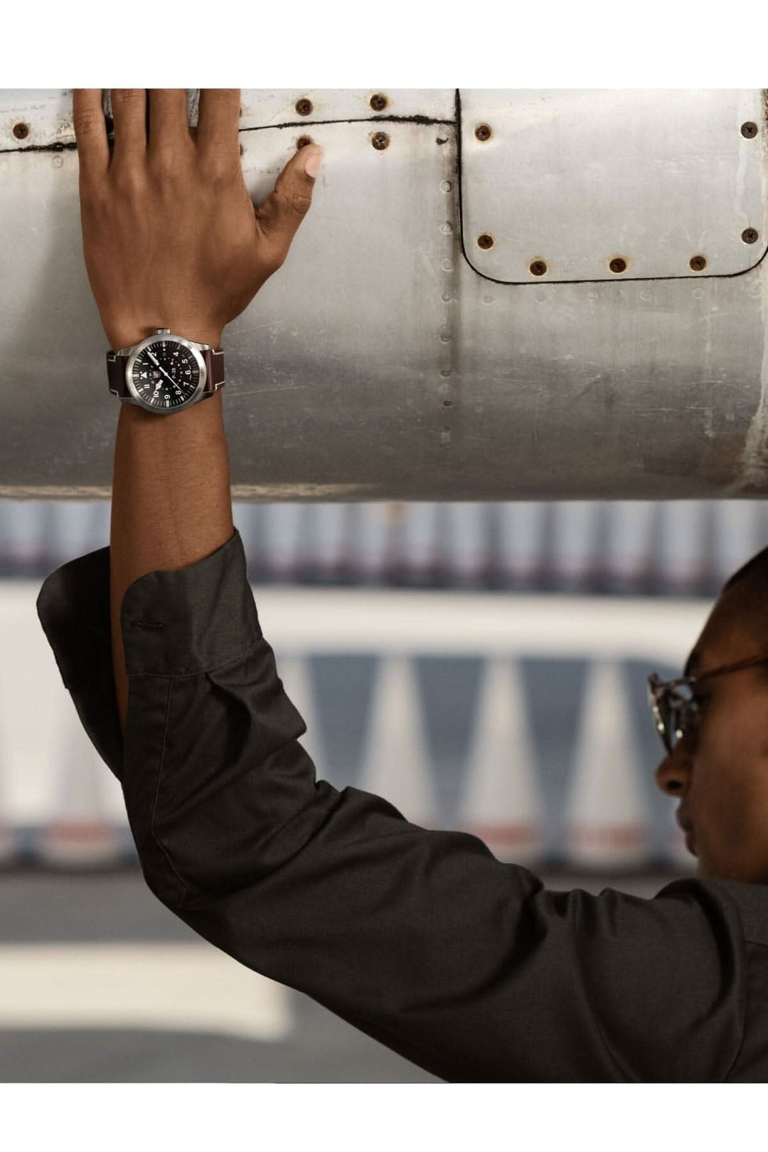 Homme portant la montre P-38 Lightning 9521 sous un élément d'avion, en style élégant avec un cadran noir.