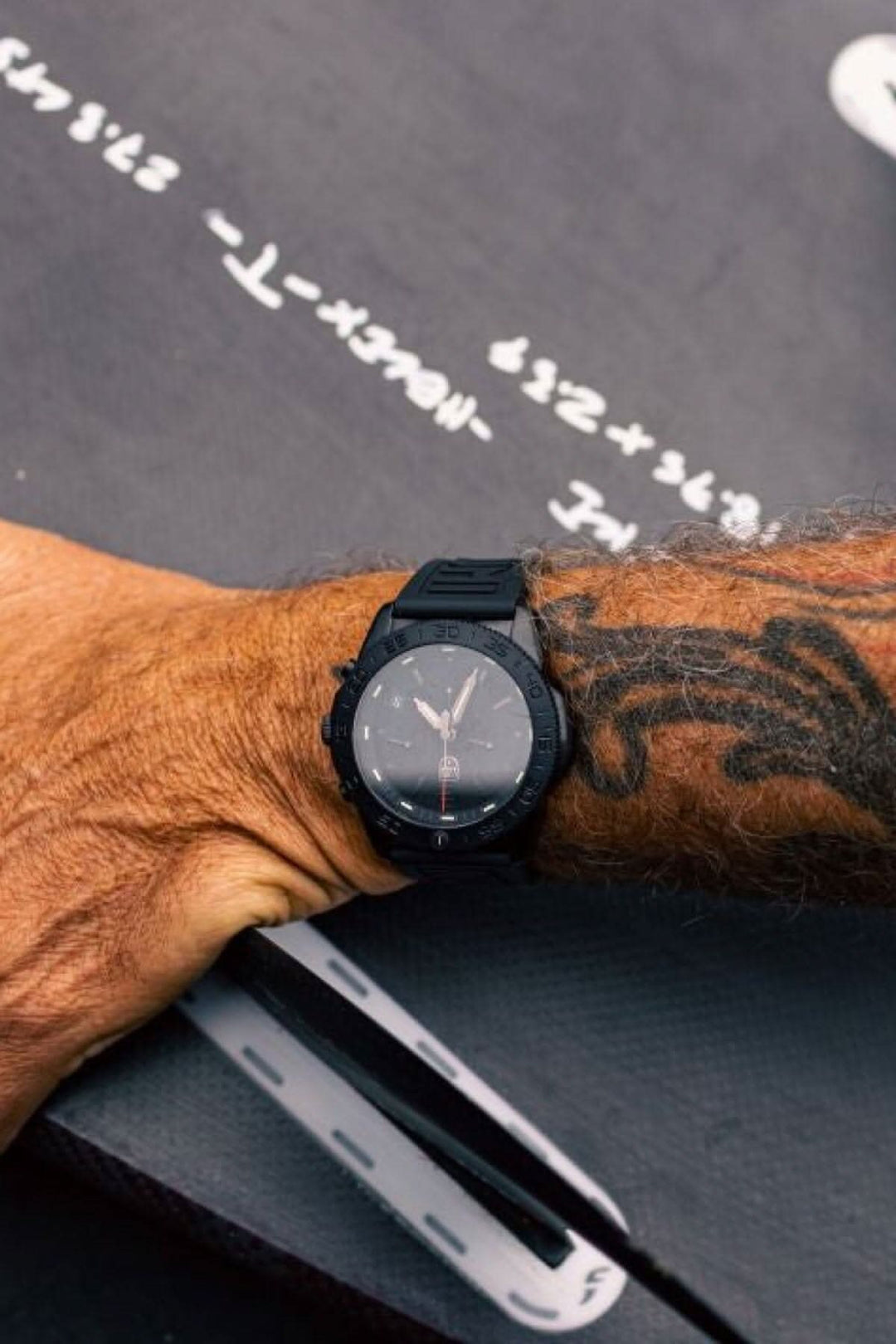 Montre Montre Pacific Diver 3141.BO sur poignet masculin avec tatouage sur fond de surface marine.