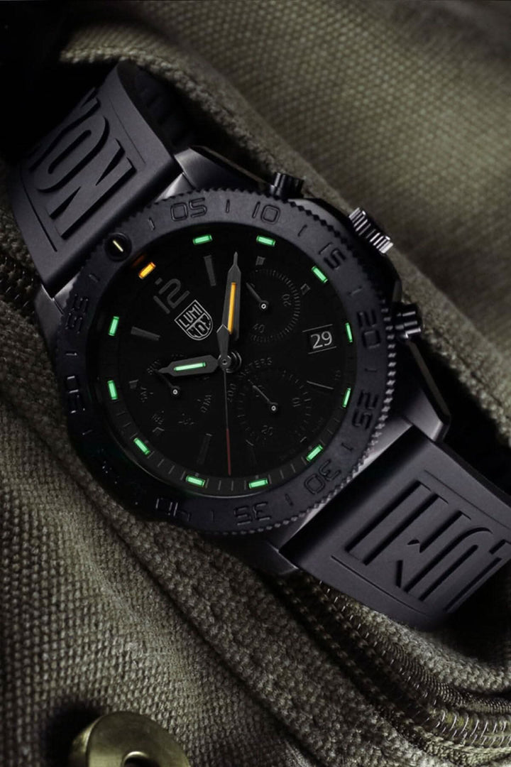 Montre Luminox Pacific Diver 3141.BO avec boîtier noir et bracelet en caoutchouc sur fond vert.