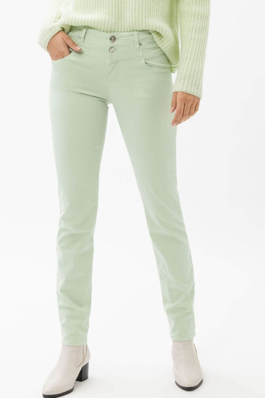 Pantalon skinny vert menthe avec 5 poches, porté avec un pull à col large, style décontracté.