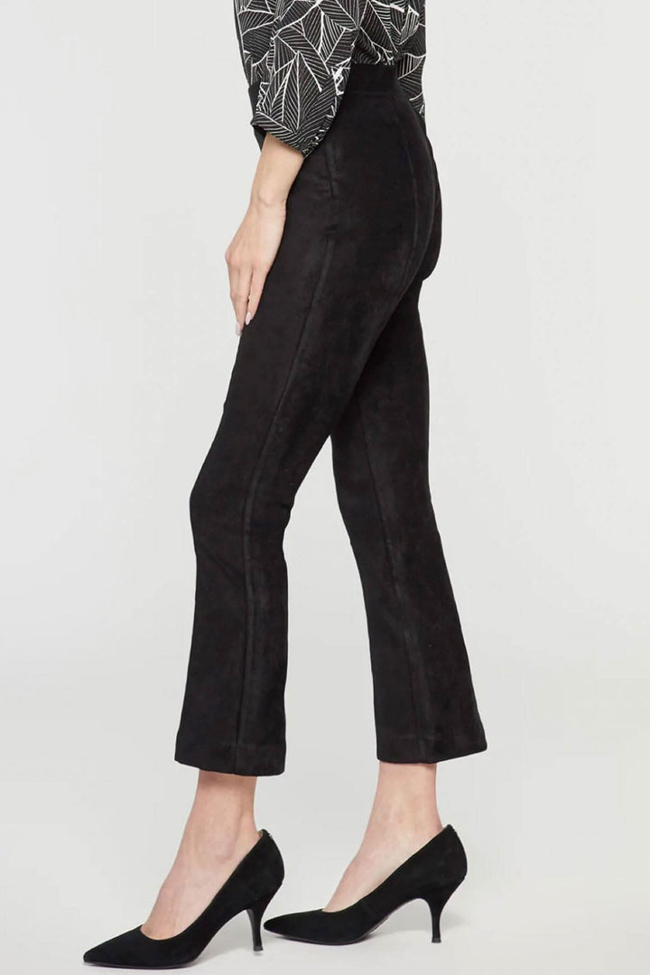 Pantalon bootcut mince en faux daim noir, coupe sculptante et légèrement évasé, porté avec des escarpins.