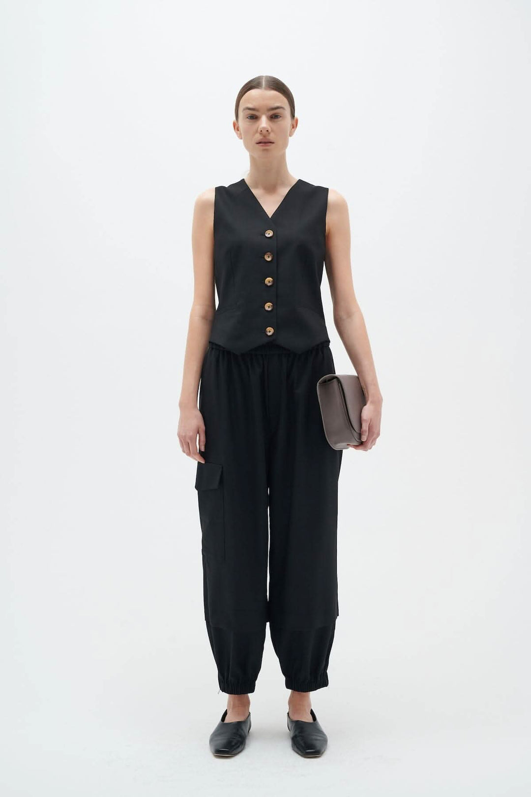 Modèle en pantalon cargo noir avec taille élastique et gilet à boutons, pose debout.