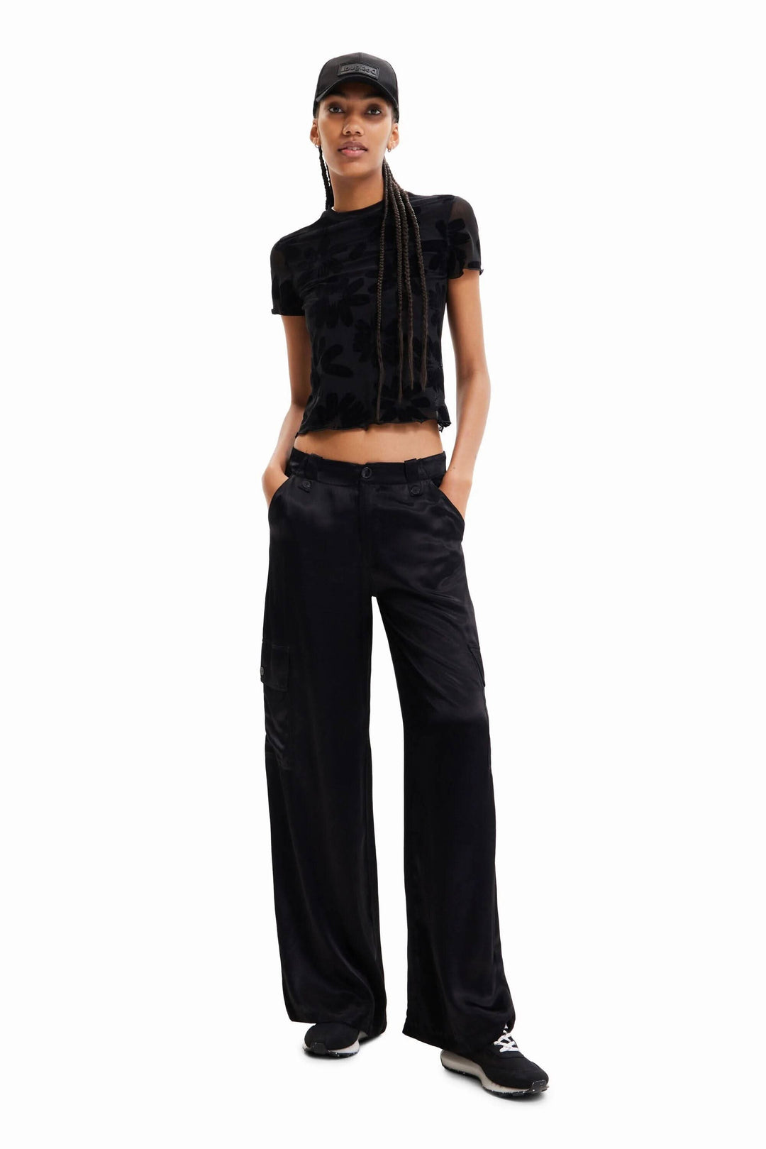 Pantalon cargo large en satin noir avec haut noir et casquette, style décontracté.