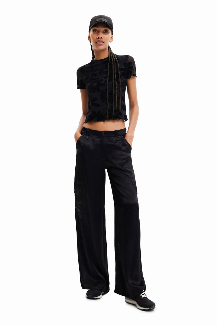 Pantalon cargo large en satin noir avec haut noir et casquette, style décontracté.
