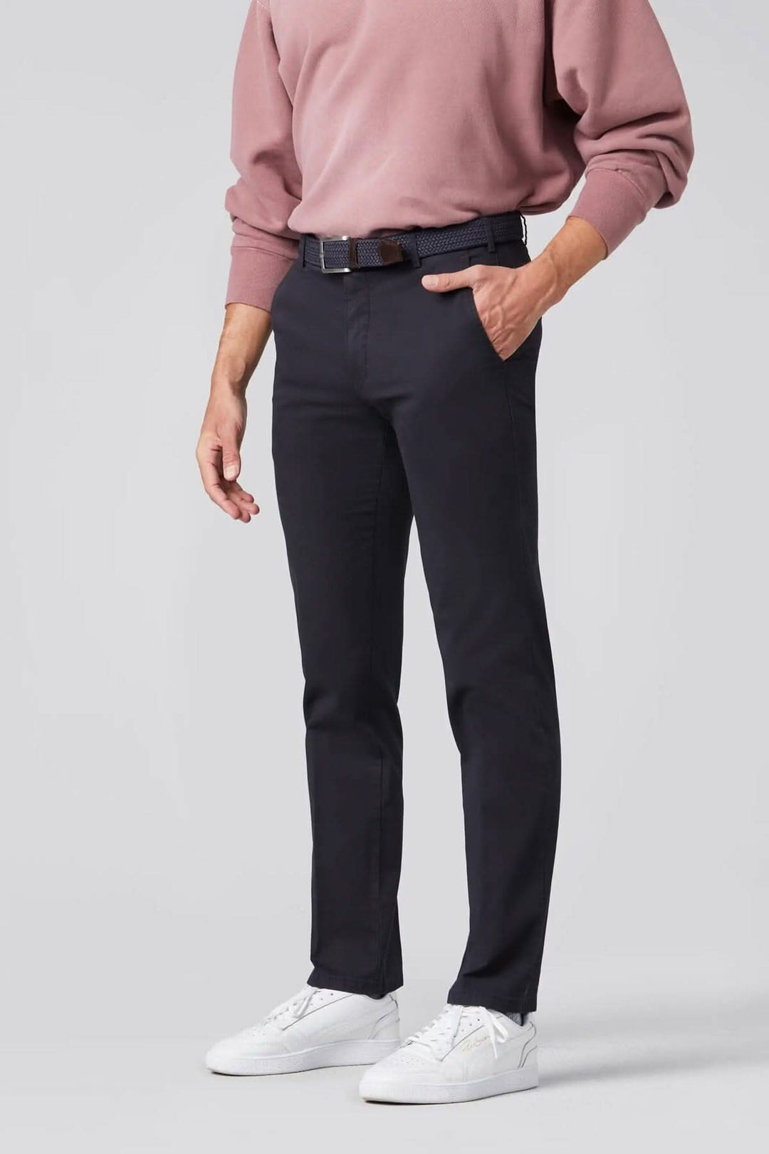 Pantalon chino ajusté, couleur marine, avec ceinture arrondie, porté avec un pull rose et des baskets blanches.