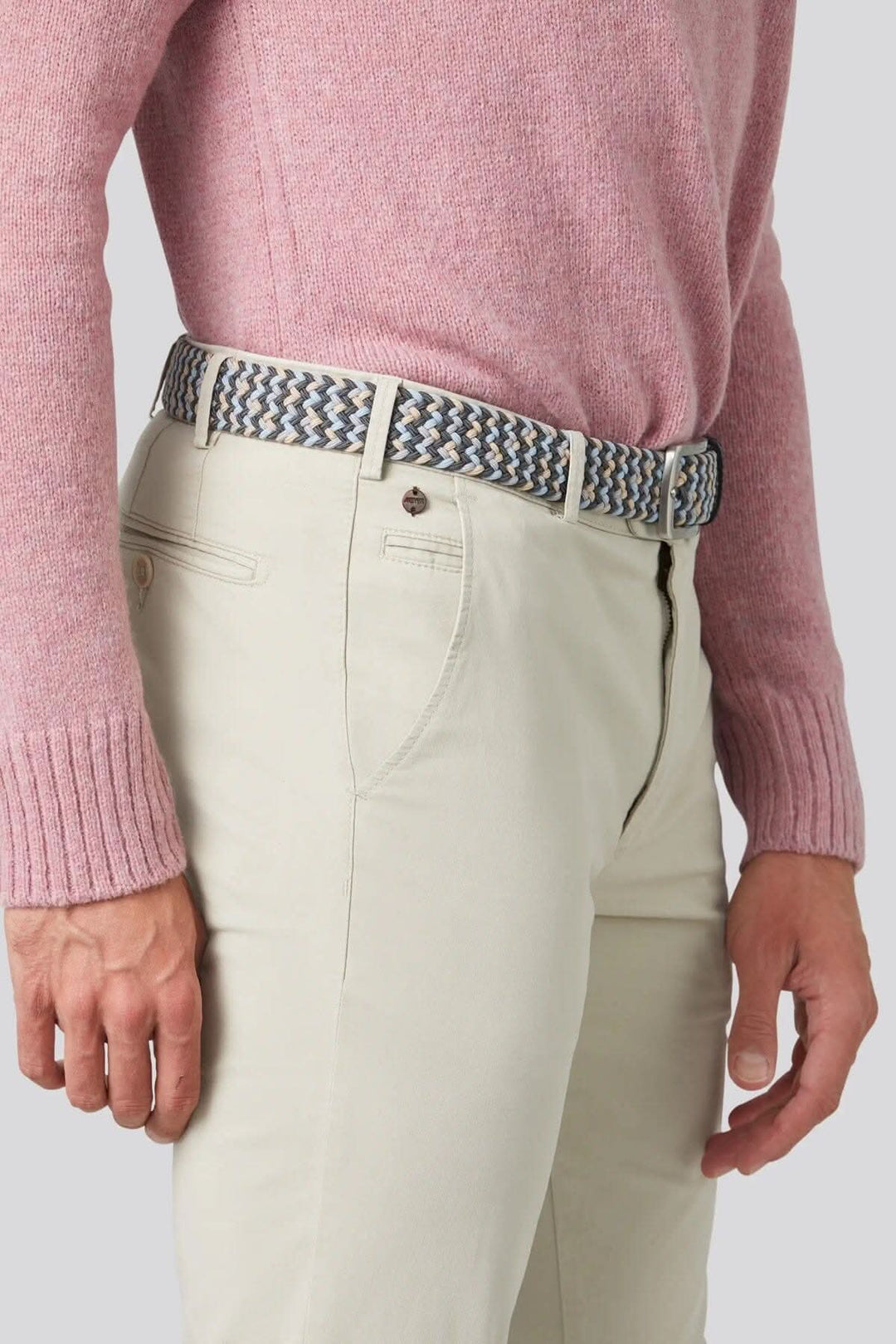 Homme portant un chino beige avec une ceinture colorée et un pull rose, offrant style et confort.