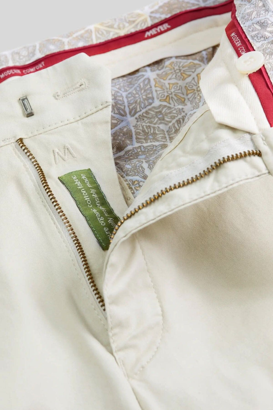 Détail d'un pantalon chino beige avec zip et doublure élégante, offrant confort et style moderne.