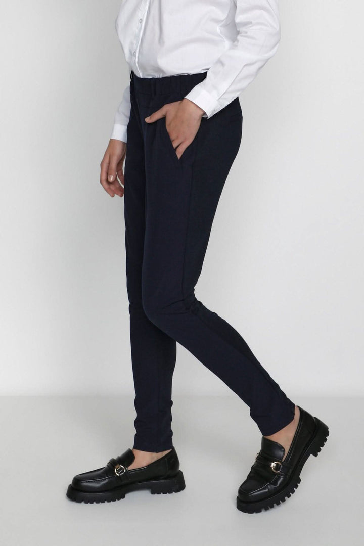 Pantalon de tailleur Jillian Sofie, coupe régulière, avec poches, porté avec une chemise blanche.