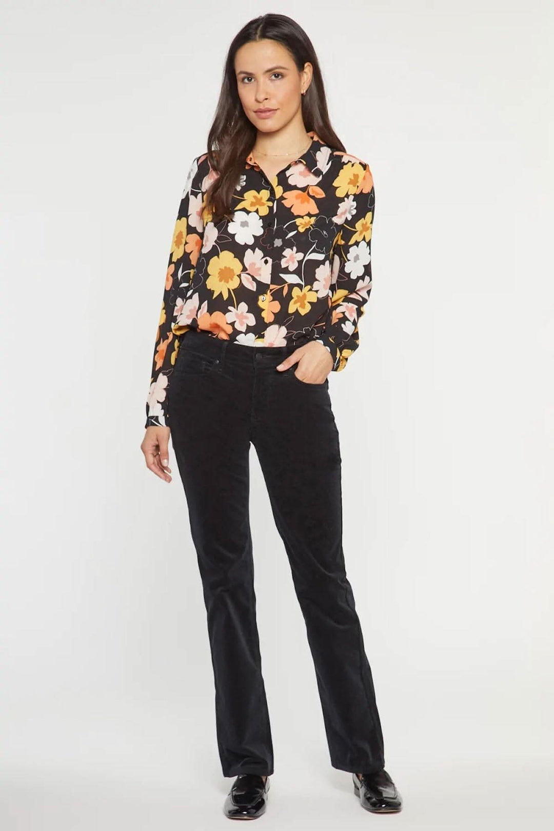 Femme portant un pantalon droit en velours côtelé noir, associé à une blouse florale colorée.