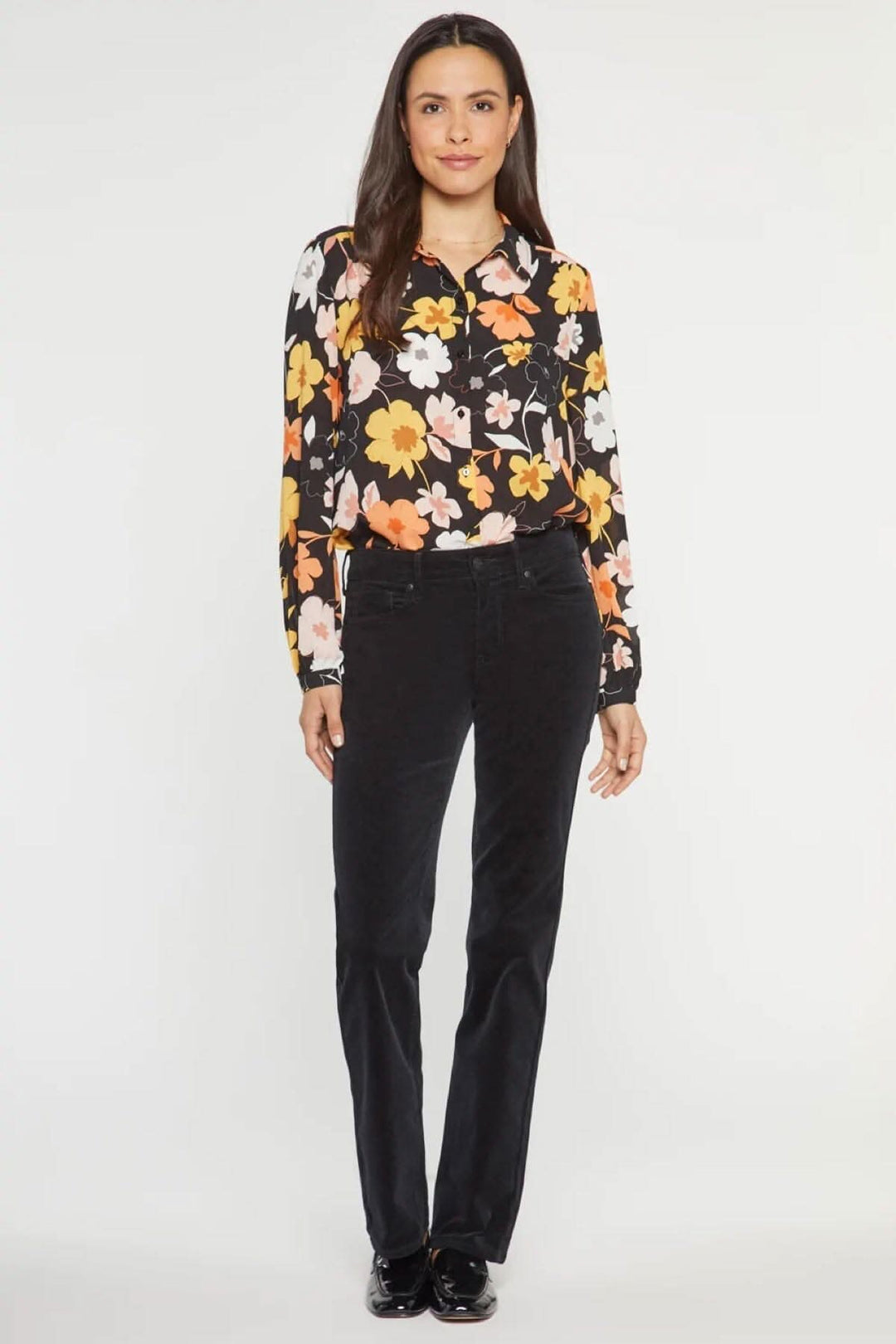 Femme portant le pantalon droit Marilyn noir en velours côtelé, associé à une blouse florale colorée.
