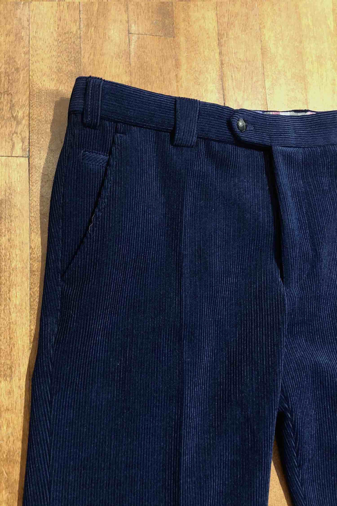 Pantalon en corduroy bleu marine, coupe régulière et éco-responsable, détails des poches et bouton.