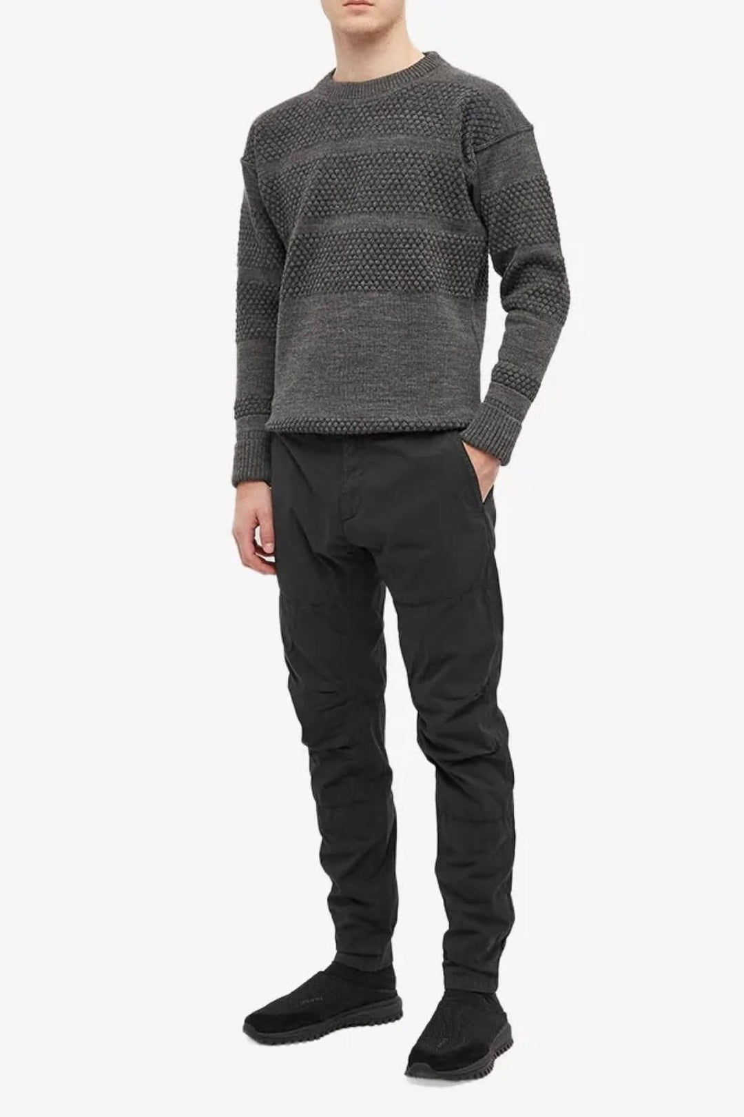 Homme portant un pantalon ergonomique en twill stretch noir et un pull gris, affichant un style décontracté.