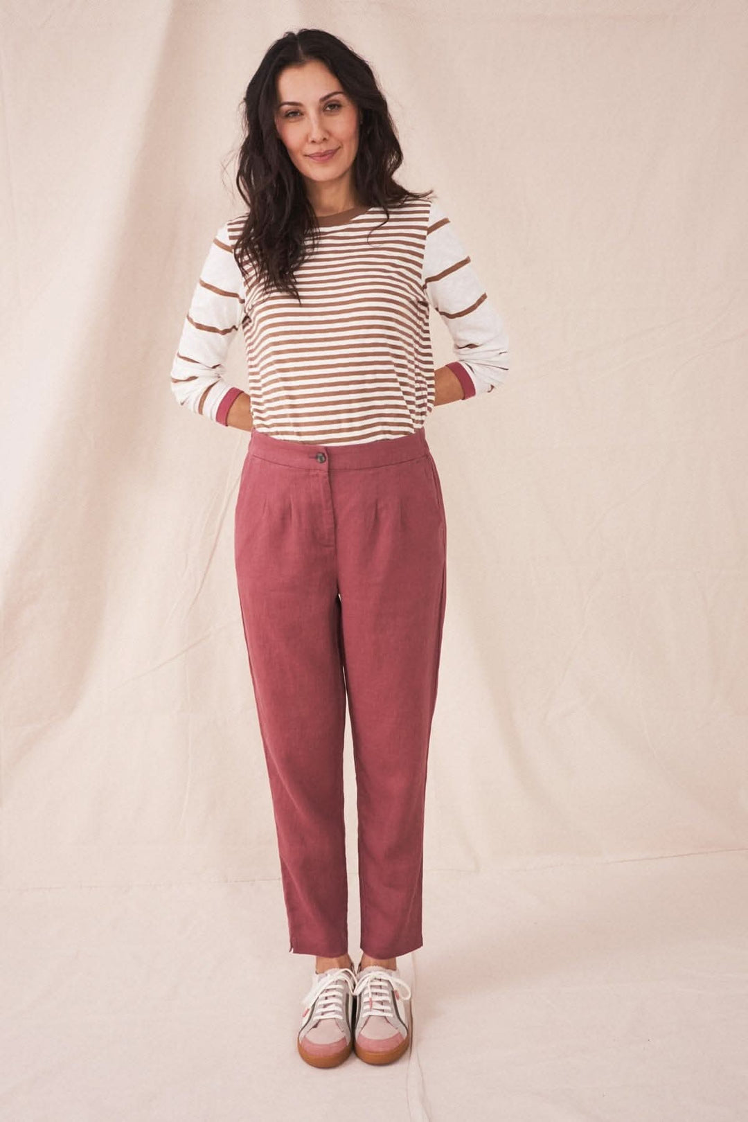 Femme portant le pantalon Maddie en lin rose, avec un haut rayé, tenue décontractée et estivale.
