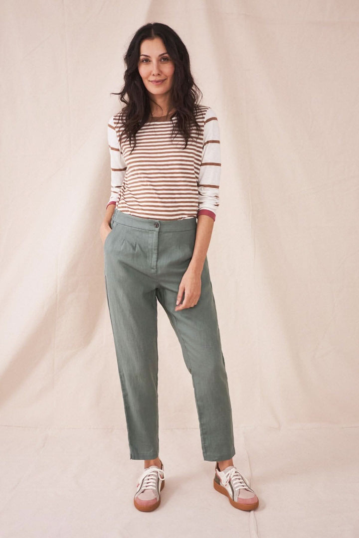 Femme portant le pantalon Maddie en lin vert avec une shirt à rayures et des baskets, idéale pour temps chaud.