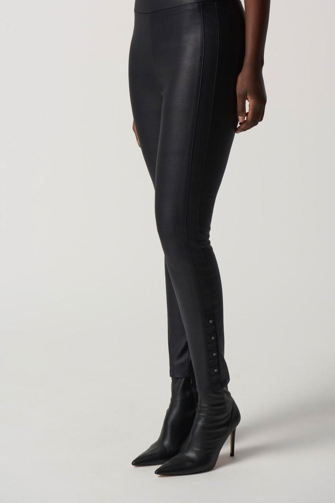 Pantalon skinny noir avec une bande de taille extensible et des clous le long de la cheville, porté avec des escarpins.