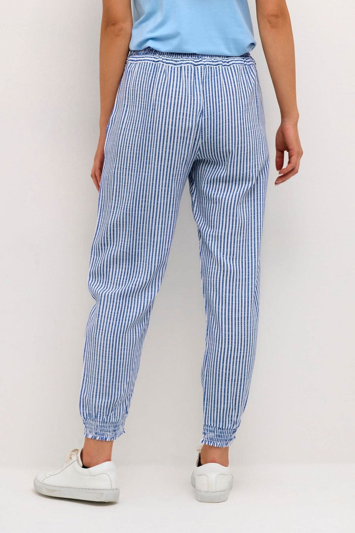 Pantalon Willis à rayures bleues, avec taille élastique et chevilles resserrées, porté avec des baskets blanches.