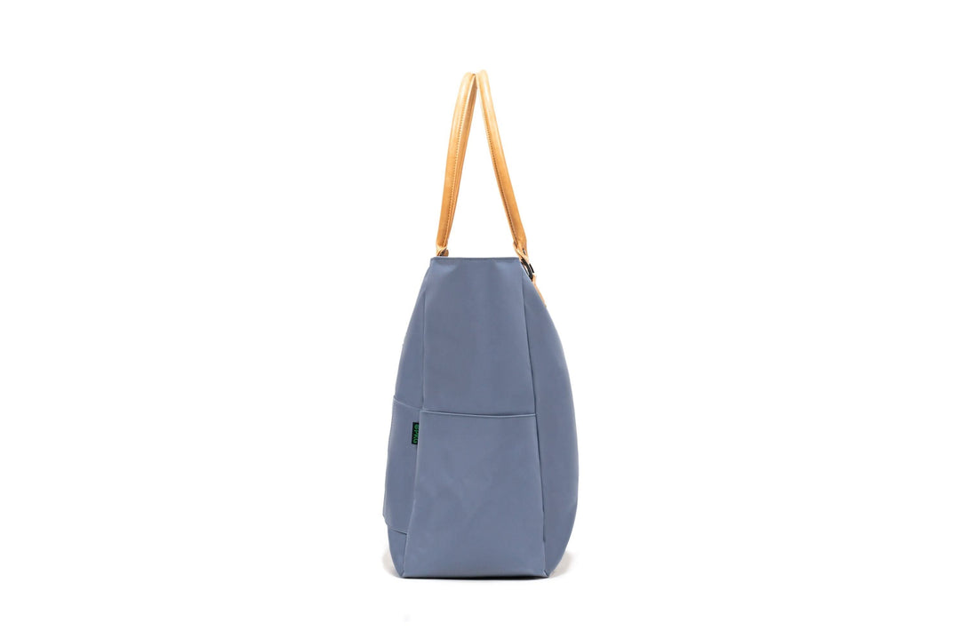 Side view of PKG Georgian 33L tote bag in blue with leather straps, highlighting its sleek design and durable fabric.