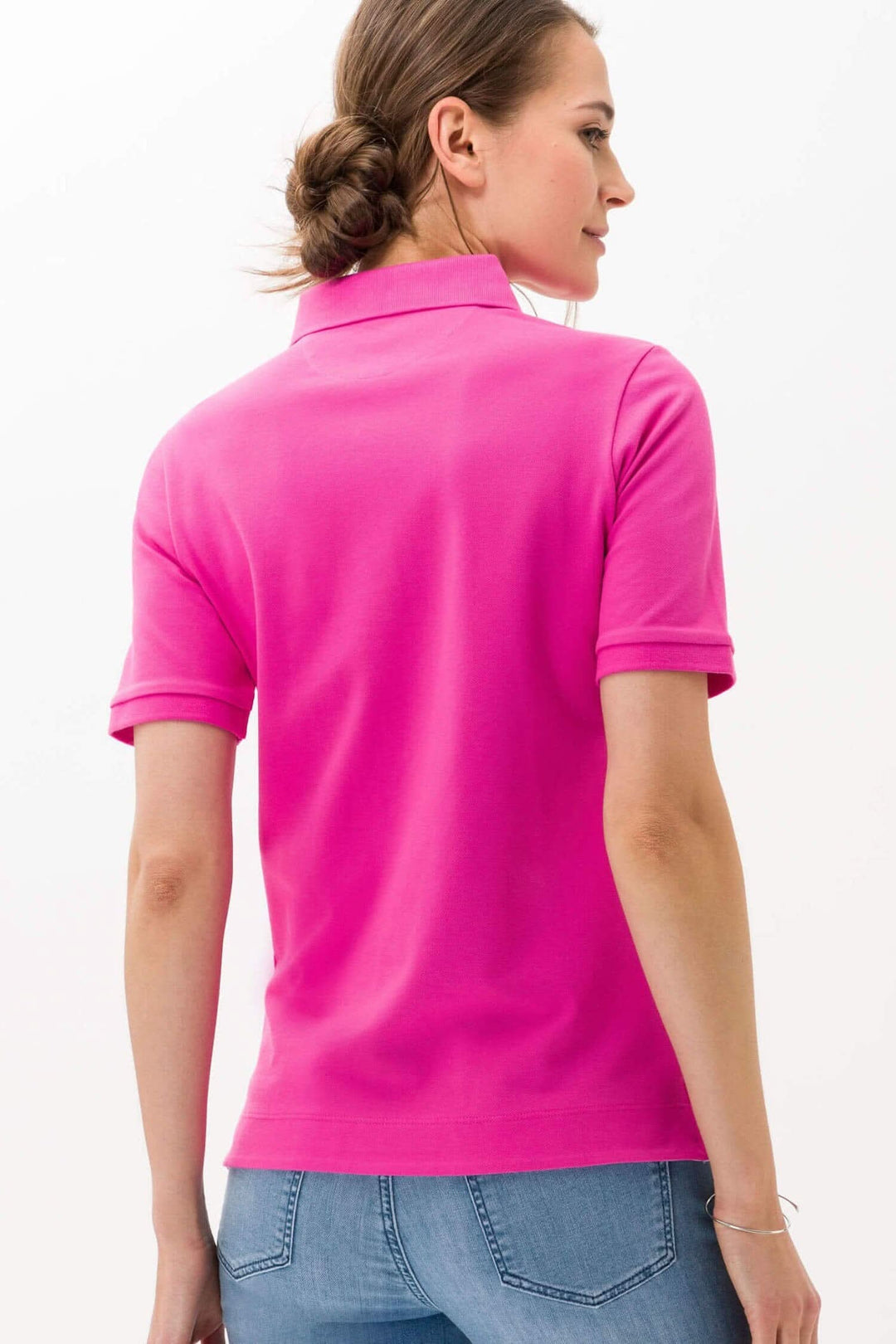Femme portant un polo rose Cleo, vue de dos, mettant en valeur la coupe confortable et moderne.