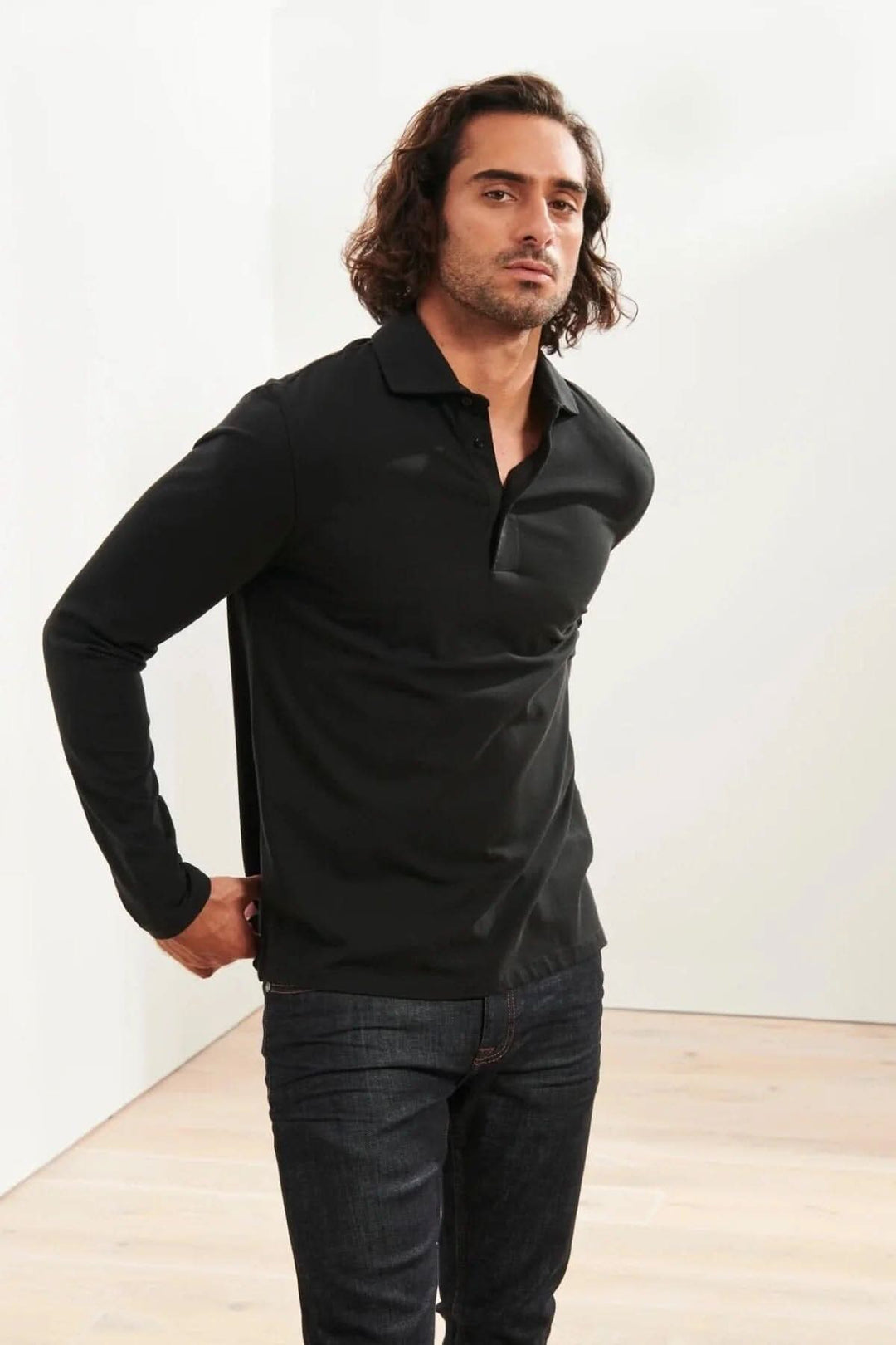 Homme portant un polo en coton stretch noir à manches longues, parfait pour un look décontracté ou habillé.