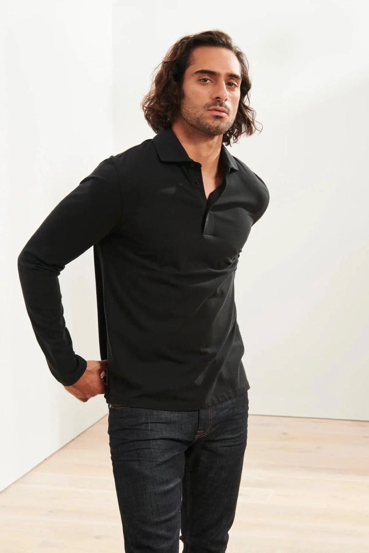 Homme portant un polo en coton stretch noir à manches longues, parfait pour un look décontracté ou habillé.