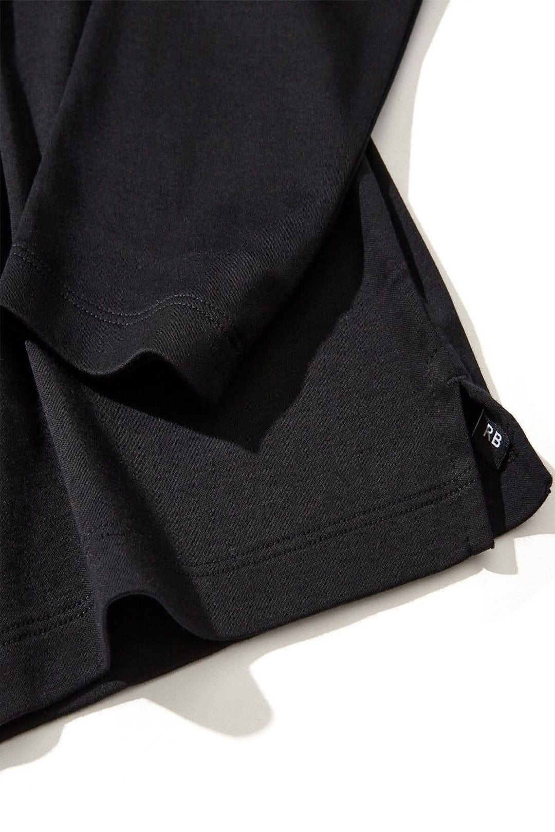 Polo Georgia en coton Pima noir avec col et patte de boutonnage en maille nid d'abeille, vue de près.