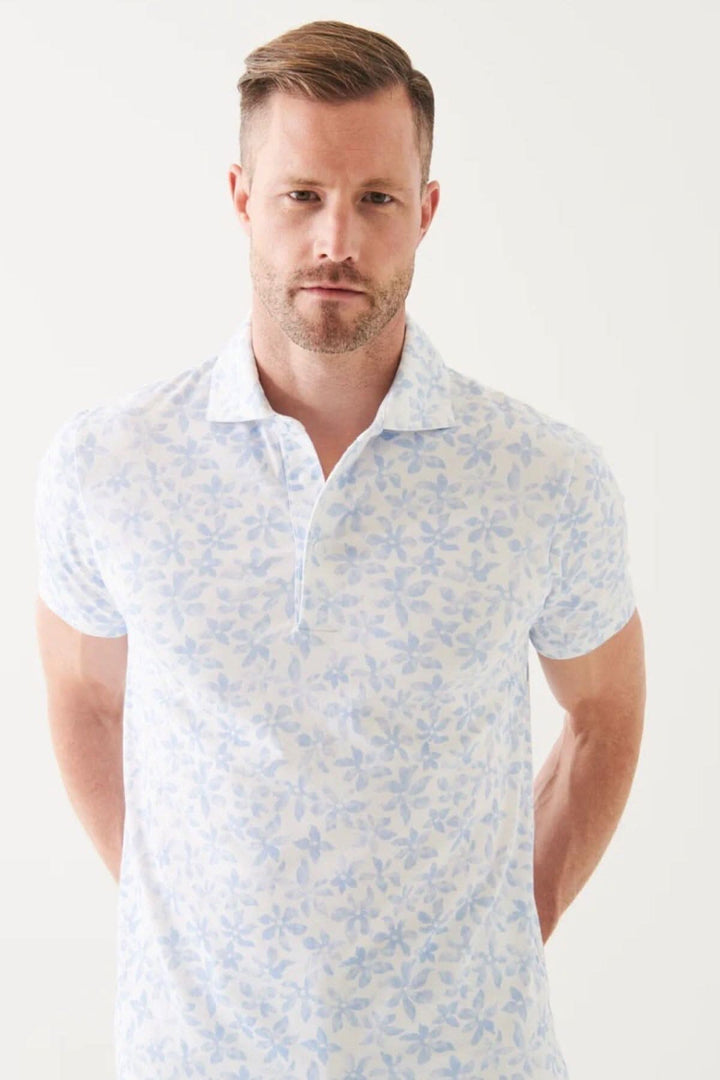 Homme portant un polo en coton pima extensible à motif floral bleu clair.