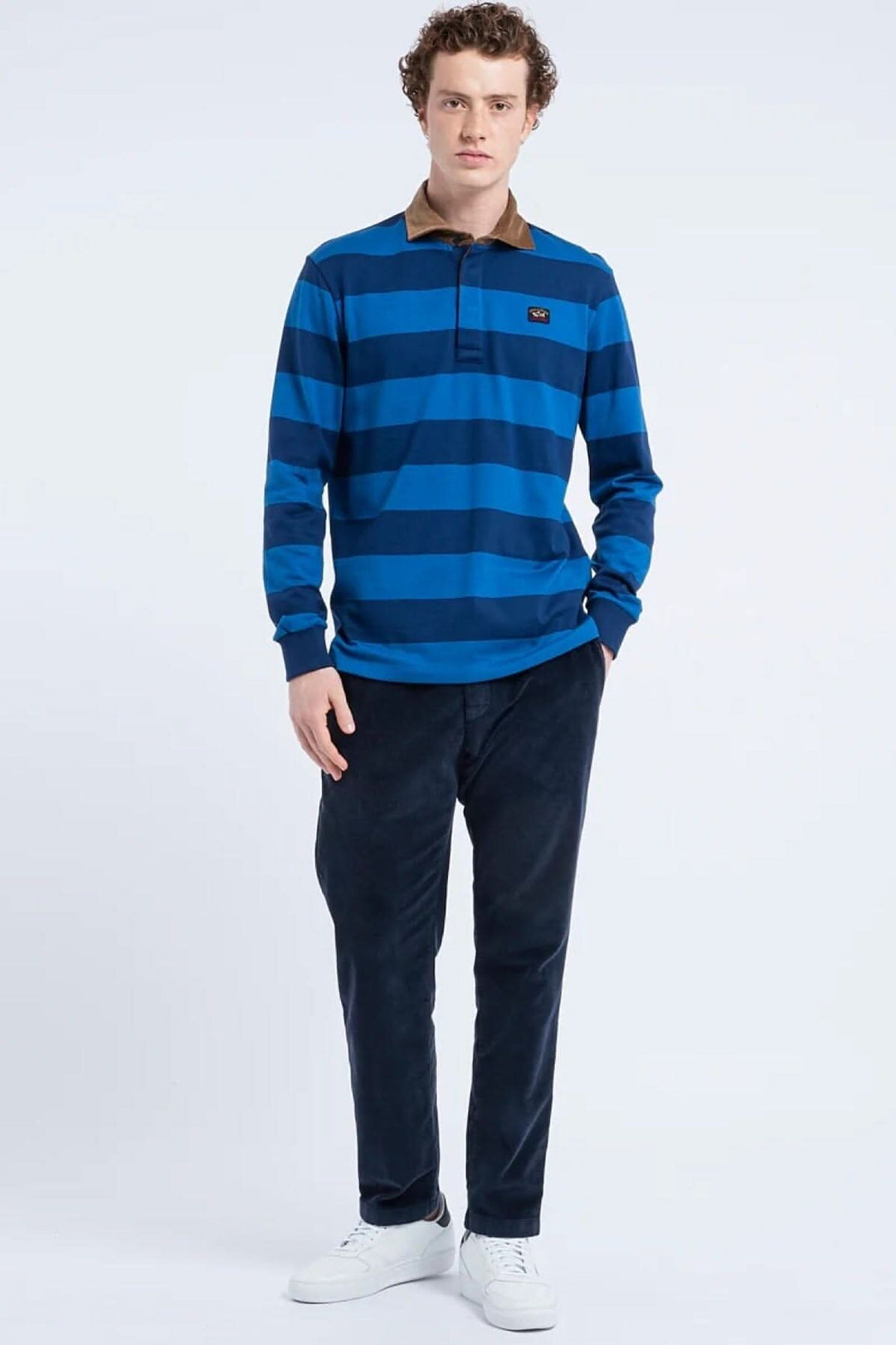 Homme portant un polo rugby rayé bleu avec col en velours, associant style et confort.
