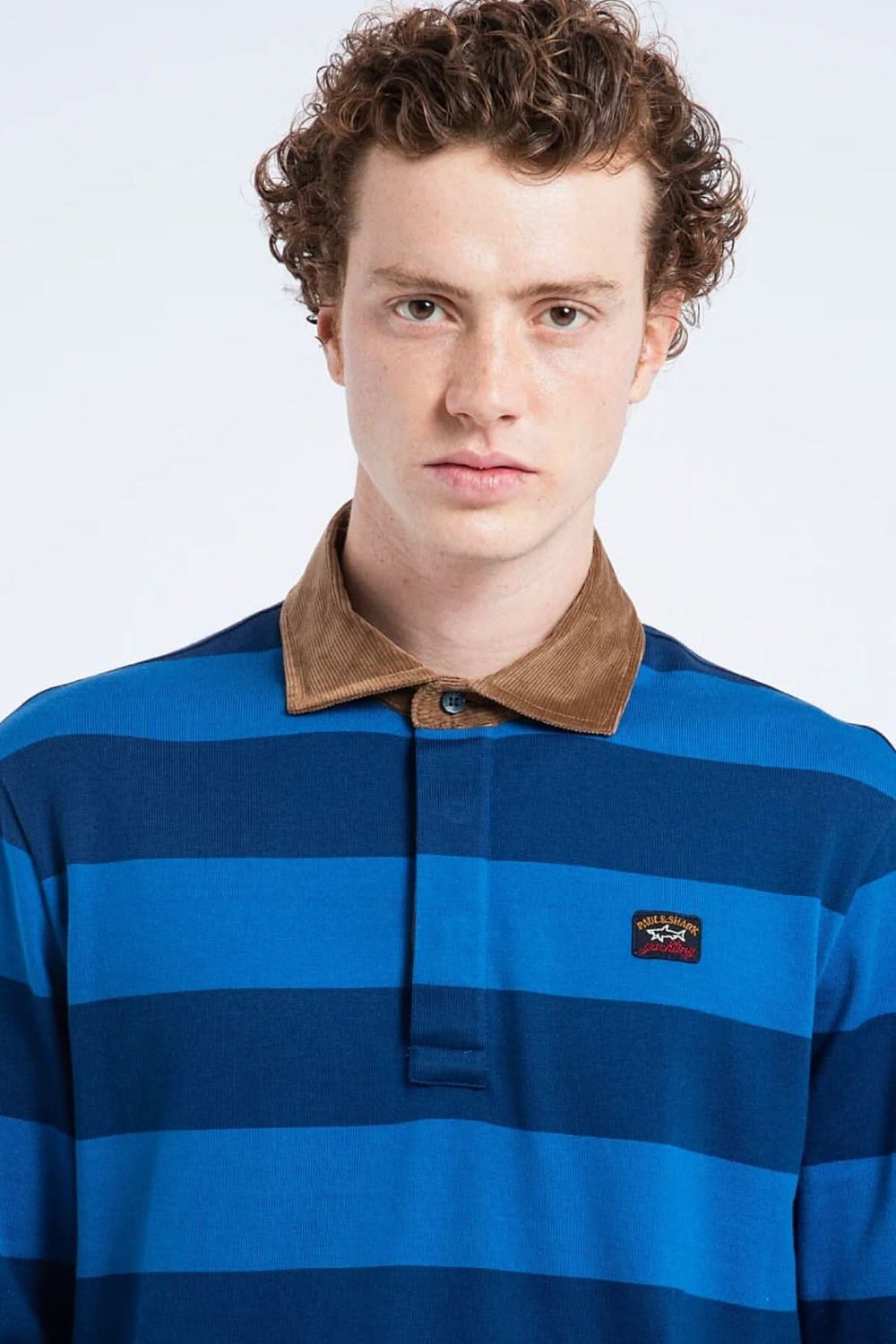 Polo rugby ligné bleu avec col en velours, porté par un modèle masculin, style décontracté.