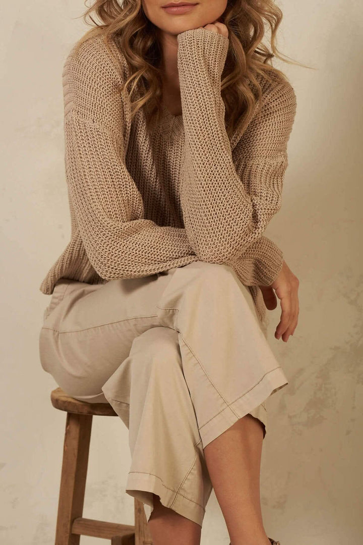 Pull à mailles en coton avec col en v, porté avec un pantalon léger, style décontracté et tendance.