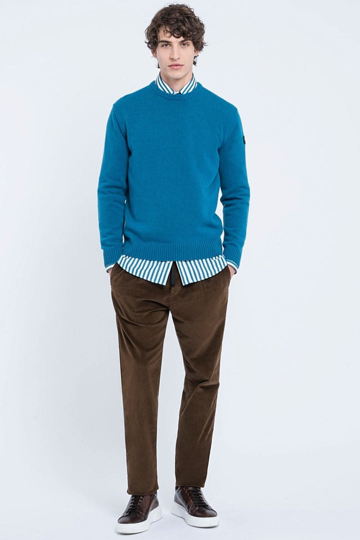 Pull en laine Shetland bleu associé à une chemise à rayures et pantalon marron, look élégant pour homme.
