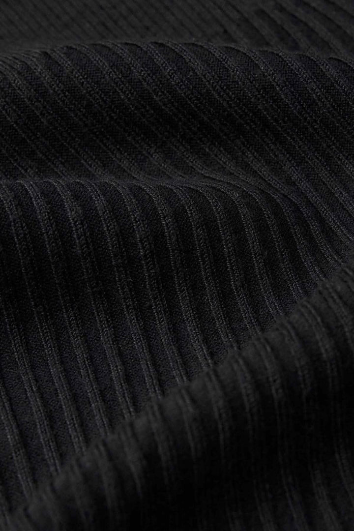 Gros plan sur le tissu côtelé noir du pull tunique, mettant en avant sa texture douce et moderne.