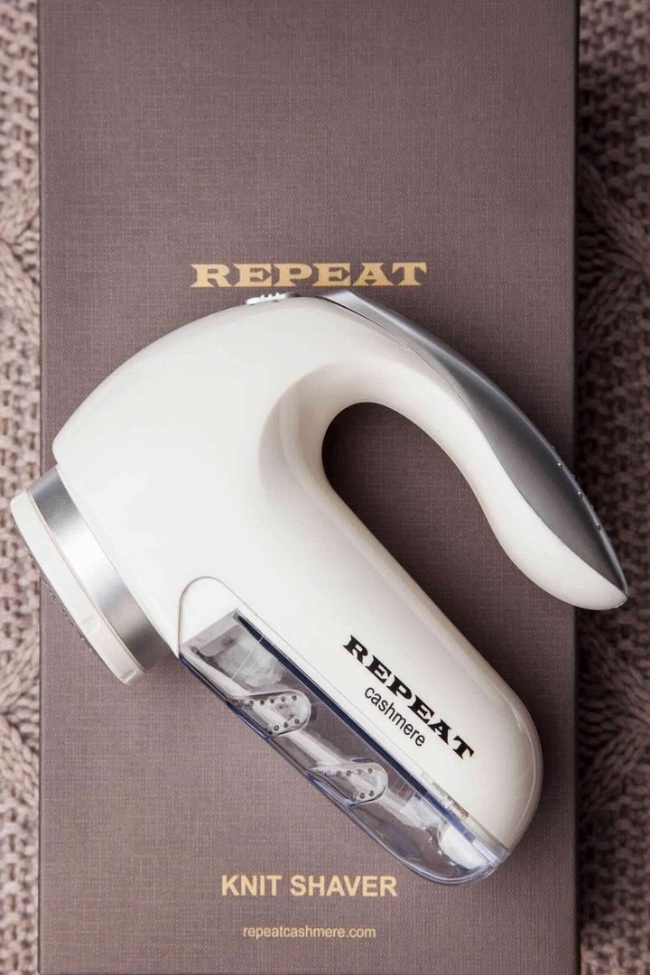 Rasoir à laine électrique REPEAT pour enlever bouloches et fibres des vêtements en laine, avec récipient transparent.