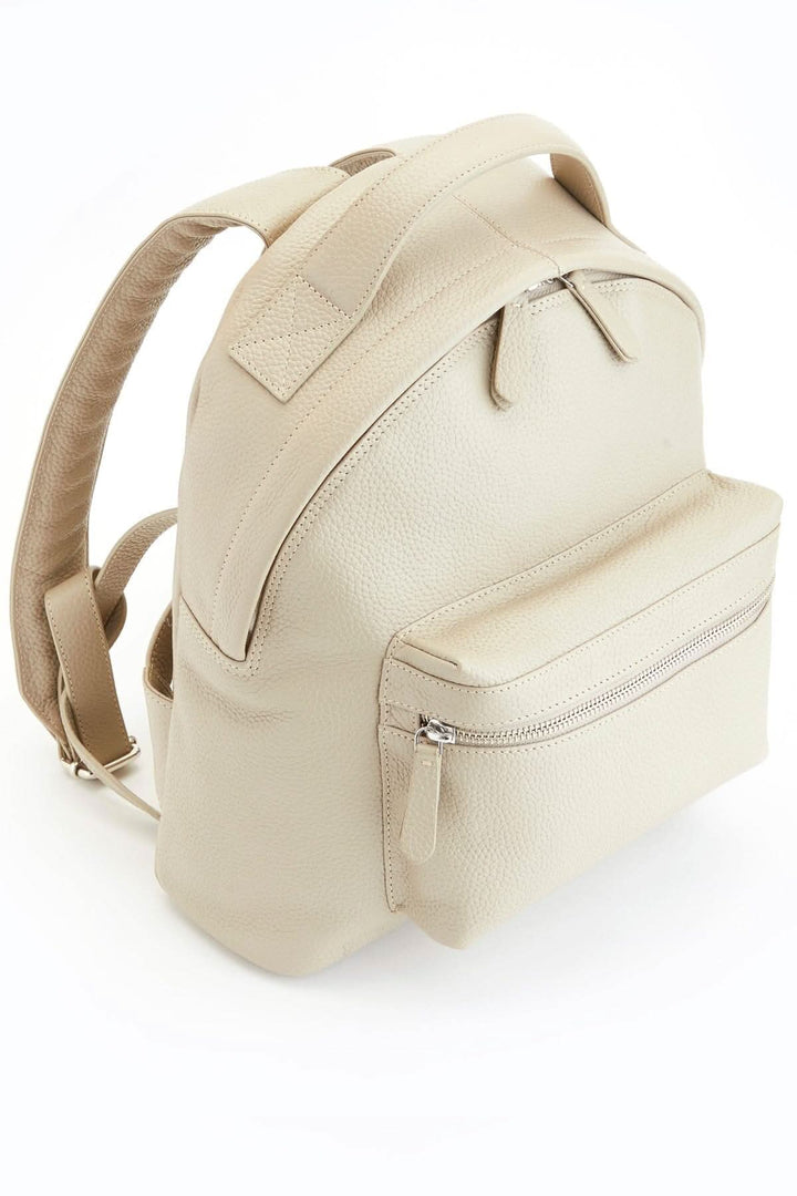 Sac à dos de voyage compact en cuir beige avec compartiment pour tablette et poche frontale zippée.