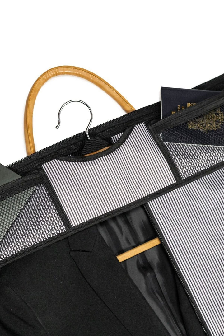 Intérieur d'une housse de costume avec un costume noir suspendu sur un cintre en bois.