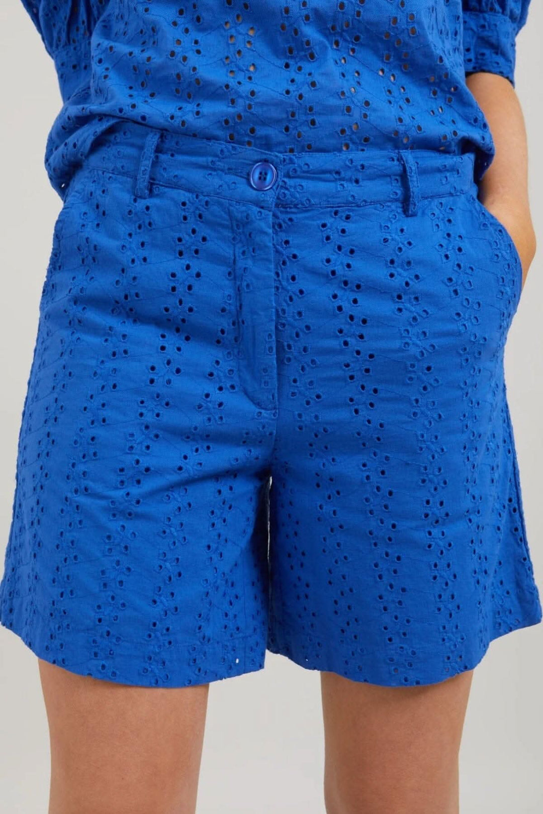 Short Lena en broderie anglaise bleue avec taille élastique et fermeture zippée, idéal pour un look estival.