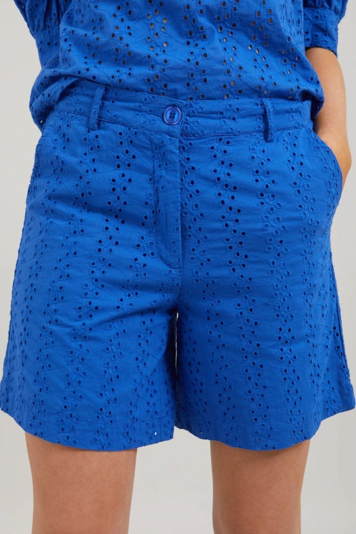 Short Lena en broderie anglaise bleue avec taille élastique et fermeture zippée, idéal pour un look estival.