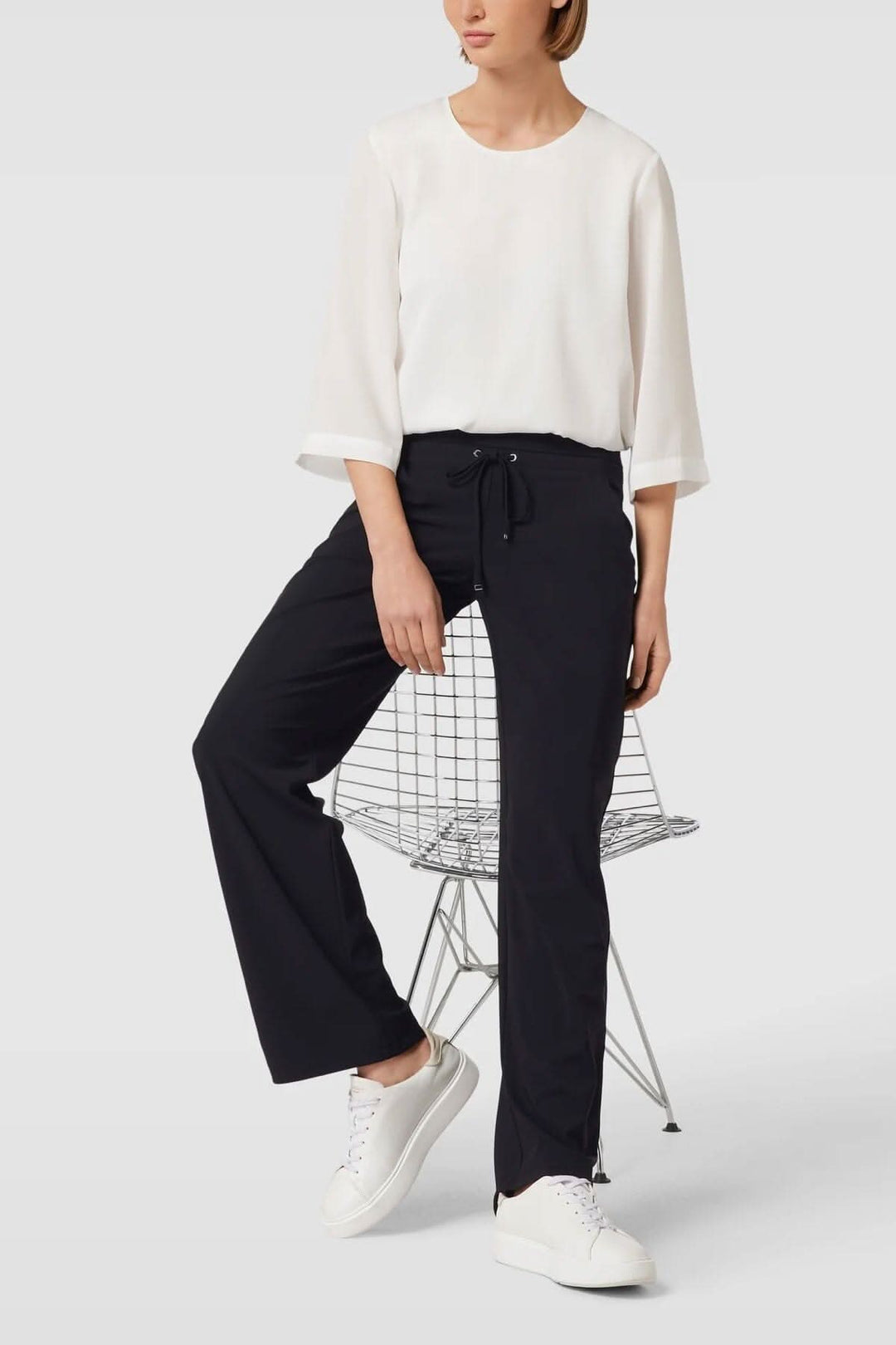 Pantalon sweat coupe droite en noir avec taille élastique, porté avec un haut blanc et sneakers blanches.