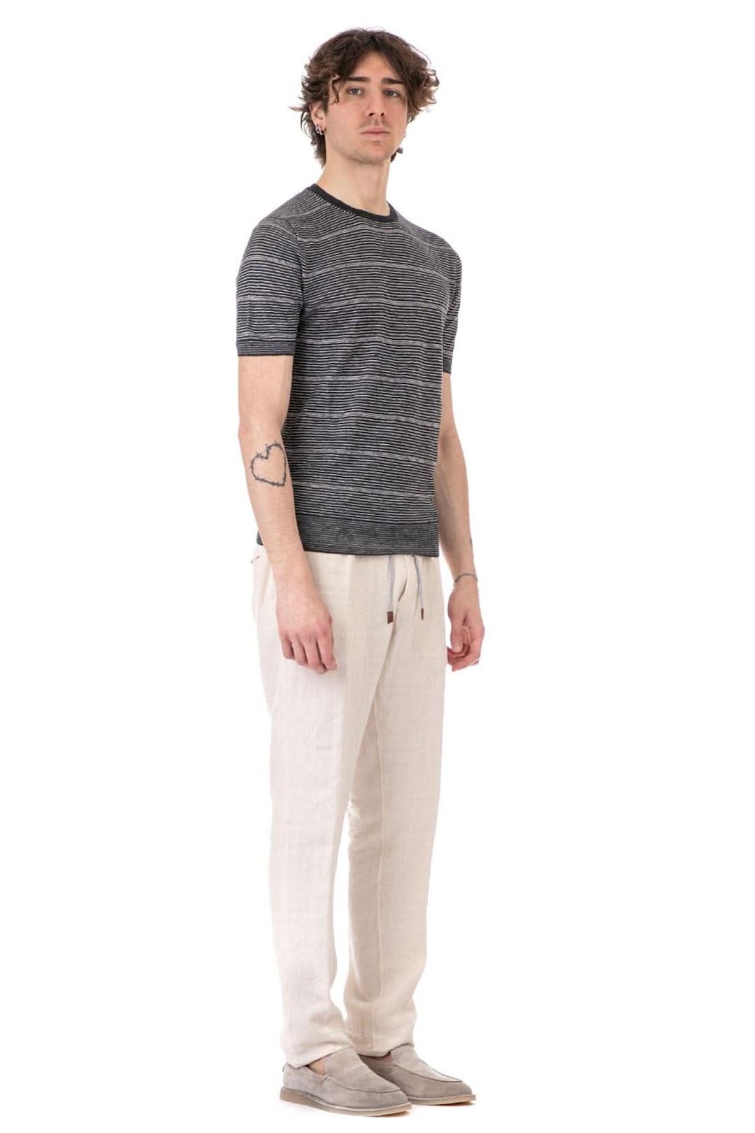 Homme portant un t-shirt à rayures gris avec un col rond, associé à un pantalon léger, idéal pour le quotidien.