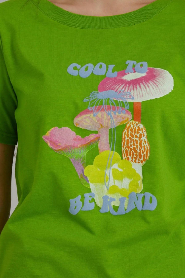 T-shirt vert avec imprimé coloré de champignons et le texte 'Cool to be Kind'.